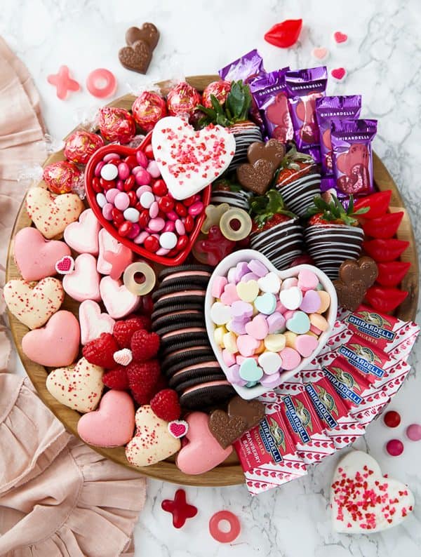 Image shows a valentine's day dessert board with cookies, fruits, and chocolates. via a pumpkin and a princess