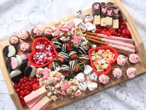 Image shows a valentine's day dessert board with cookies and muffins and candies.