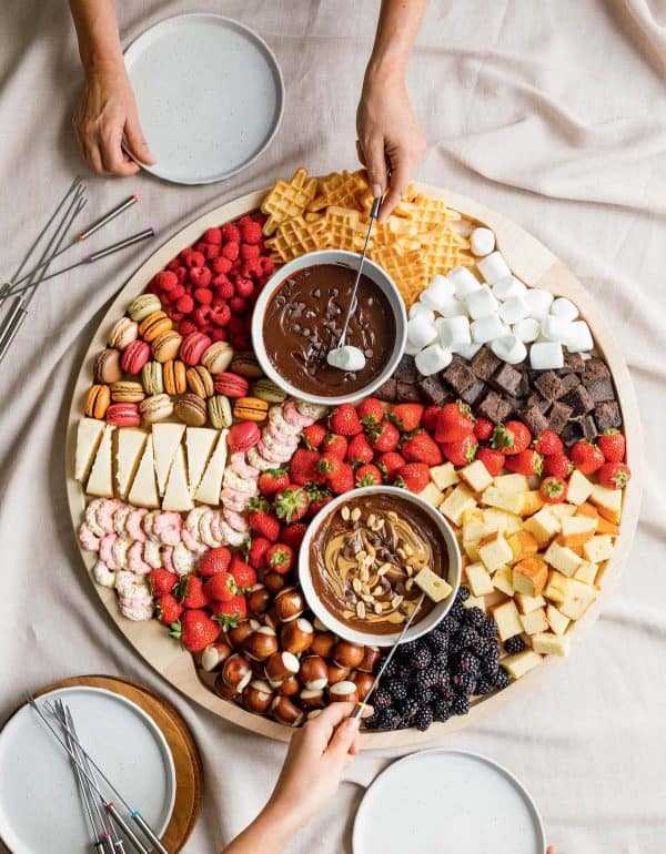 Image shows a dessert charcuterie board with nuts, berries, cheese and chocolate fondue. via Camille styles