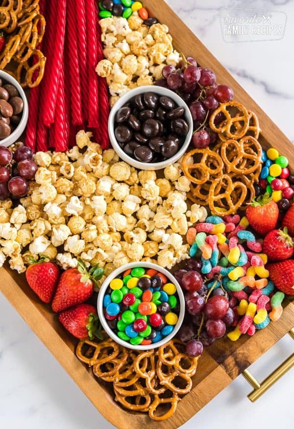 Image shows a dessert board with m&ms, grapes, strawberries, pretzels and popcorn. from fav family dinners
