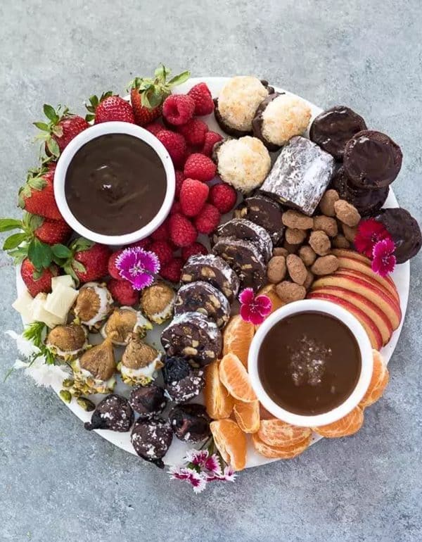 Image shows a chocolate dessert charcuterie board with berries, cookies, chocolate dip. via flavor the momens
