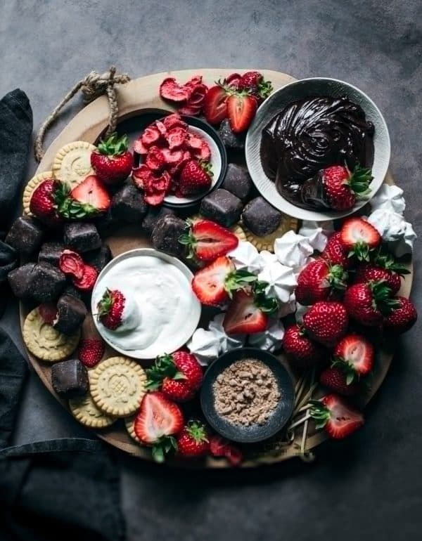 Image shows a dessert board with dark chocolate, fruits, and nuts. via little figgy food