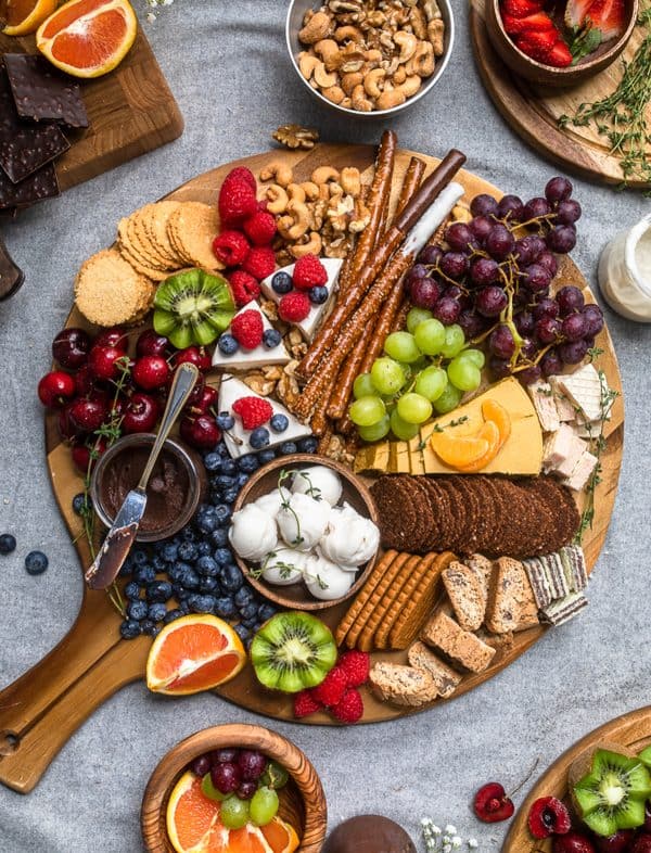 Image shows a vegan dessert board with fruits, cookies, and other ingredients. via make it dairy free