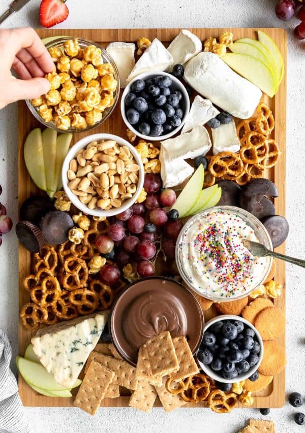 Imag eshows a dessert board with pretzels, nuts, fruits, crackers, cookies and nuts. via midwest foodie