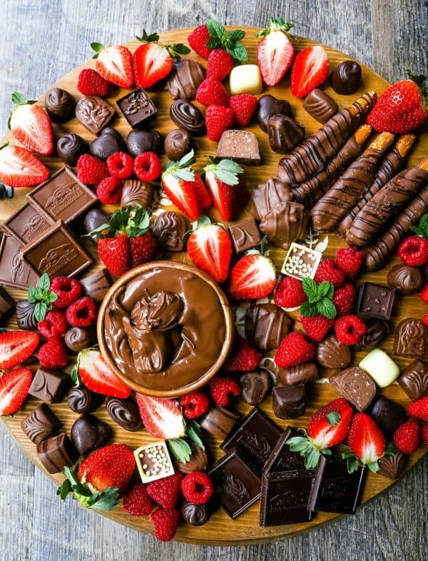 Image shows a chocolate dessert board with chocolate covered pretzels, strawbrries, dip, and more.from modern honey