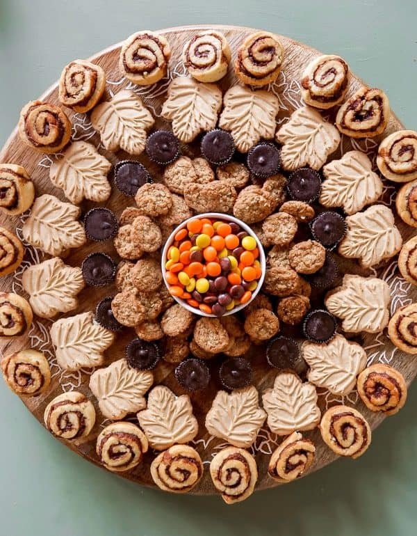 Image shows a fall-themed dessert board with cookies, chocolates, and sweets. via reluctant entertainer