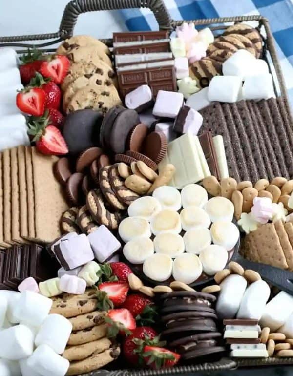 Image shows a s'mores dessert board with chocolate chip cookies, marshmallows, cookies, fruits, from simple party food