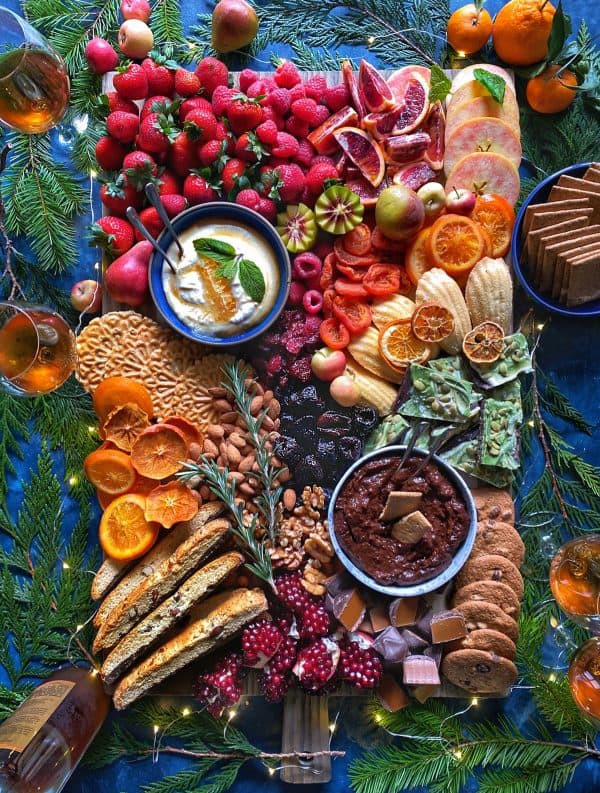 Image shows a dessert charcuterie board with brea, sweet dips, cookies, bark and dips. via the delicious life
