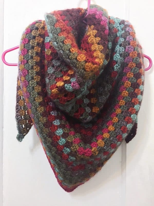 granny square shawl on pink hanger over a door skip to my lou