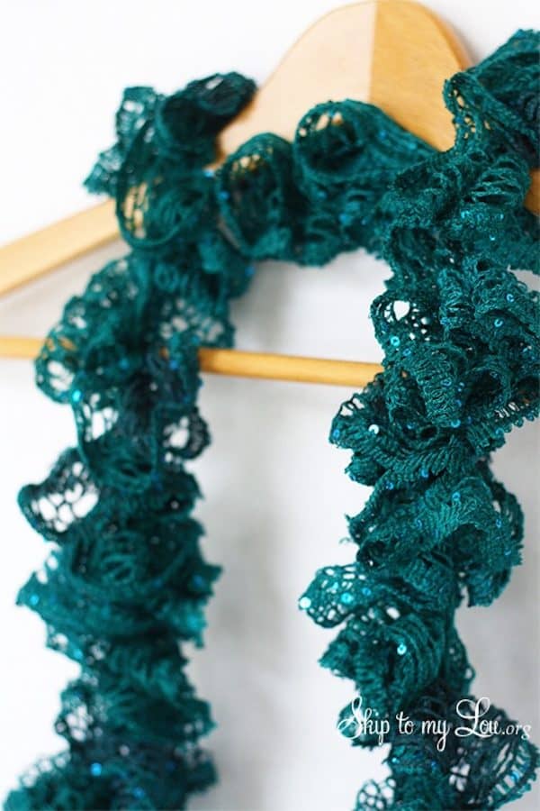Green ruffle crochet scarf hanging in a hanger skip to my lou