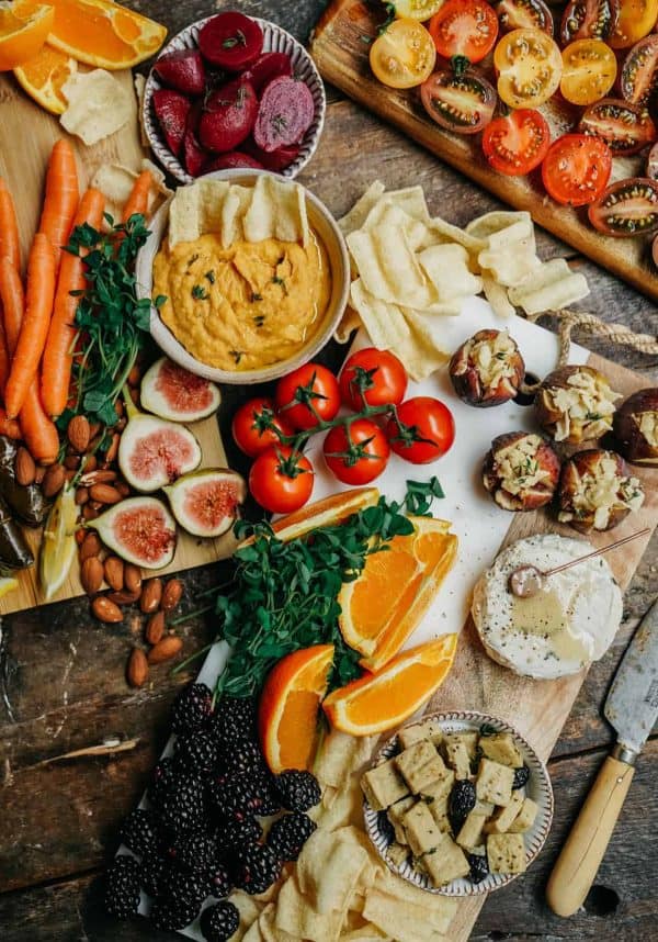 Image shows a large hummus board with vegetables and fruits.
