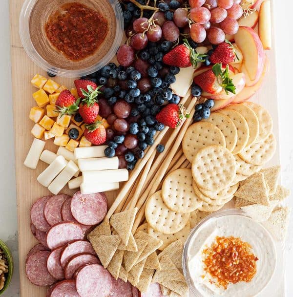 Image shows a hummus charcuterie platter with fruits, cheese, and crackers.