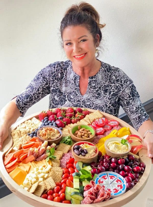 Image shows a large hummus platter with vegetables, cheese, fruits, and different dips.
