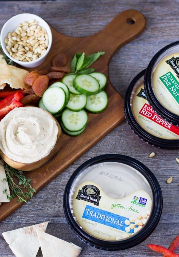 Image shows a hummus platter with vegetables, nuts and dried fruits.