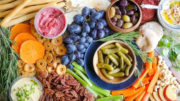 Image shows a vegan hummus platter with fruits and vegetables.