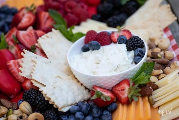 whipped cheese board recipes inspired by charm- a fruit filled board with raspberries, blueberries, strawberries, and a variety of cheese.