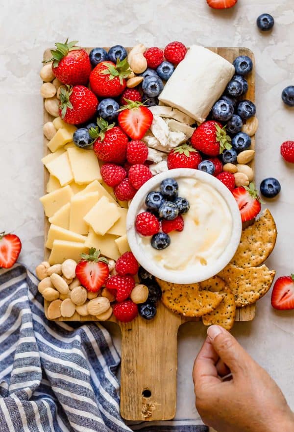 whipped cheese board recipe from plays well with butter. a board with a fruit dip, fruits, cheese and crackers.