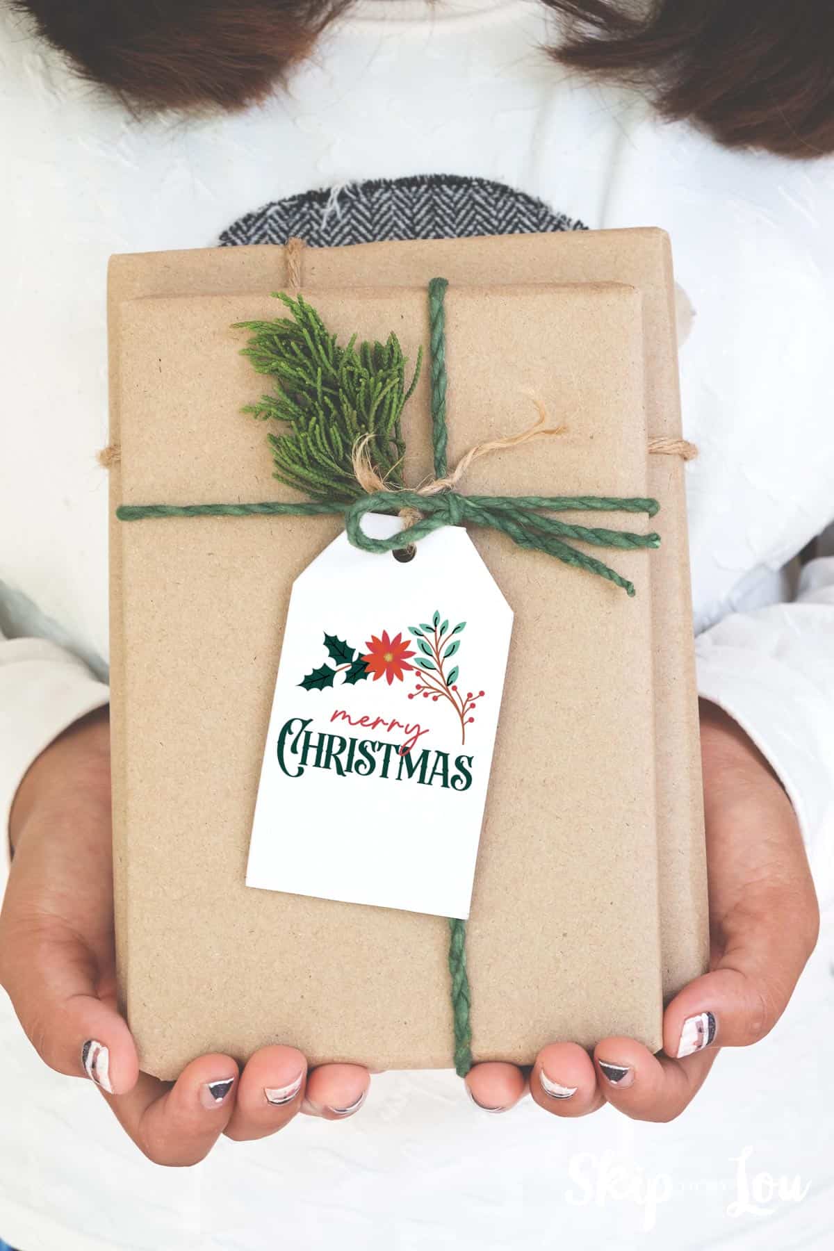merry christmas tag on kraft paper wrapped package girl holding by Skip to my Lou.