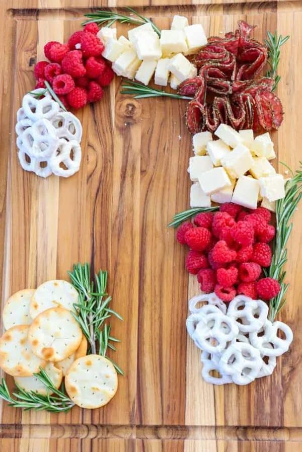 candy cane charcuterie board ideas- a board with meats, cheeses, and fresh fruit and pretzels