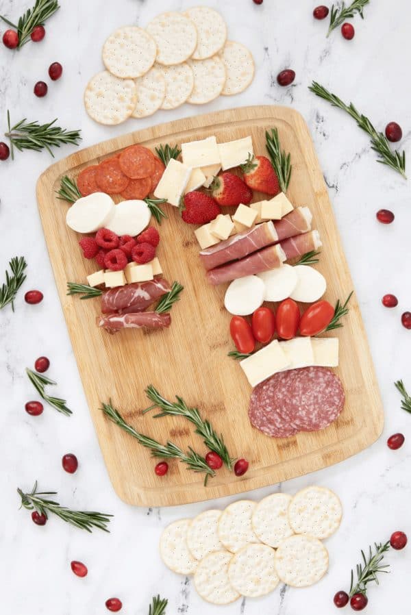 candy cane charcuterie board ideas- a simple board with red fruits, white cheese, and different meat.
