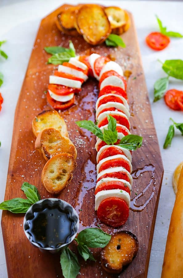 candy cane charcuterie board ideas- a board with mozzarella, tomatoes, crostinis, and balsamic glaze.
