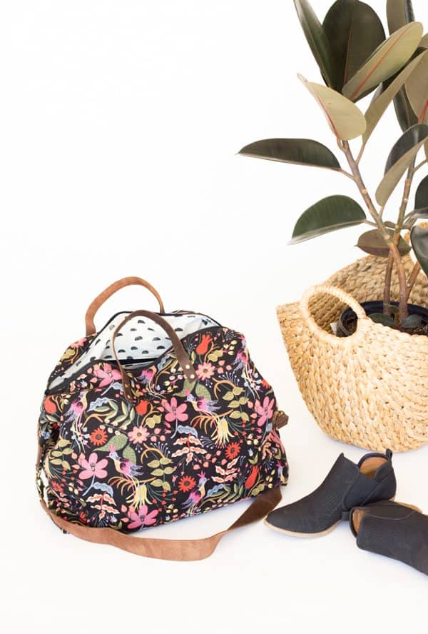 Weekend bag with flowery fabric next to shoes and a thraded bag with a plant inside.