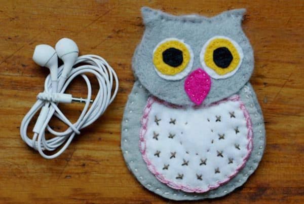 Owl-shaped pouch for ear buds and ear buds next to it.