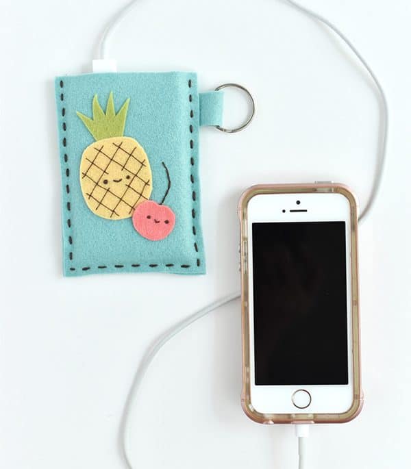 Power bank case with pineapple and cherry design and an iPhone with a charging cable next to it.
