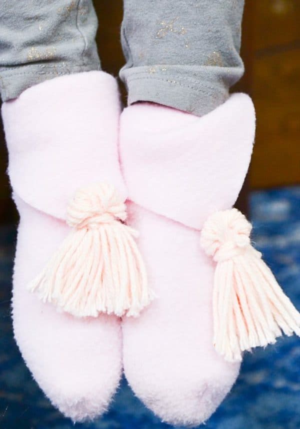 Kid wearing pink sewn slippers.