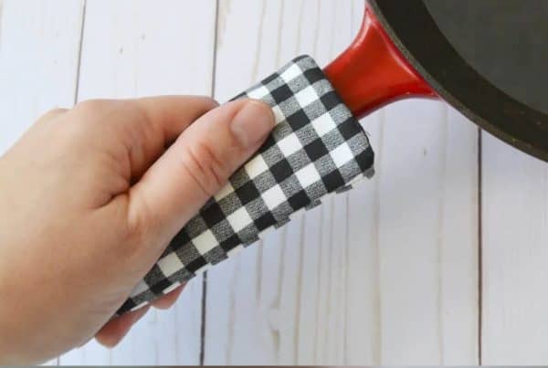 Hand holding a cast iron skillet handle cover.