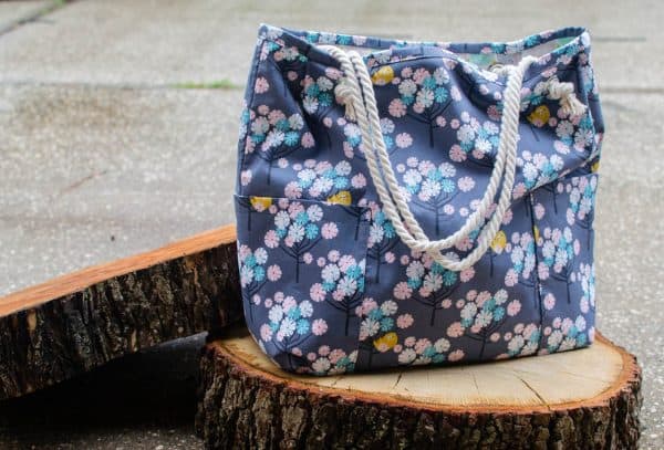Cute shopping bag with rope handles on a log.