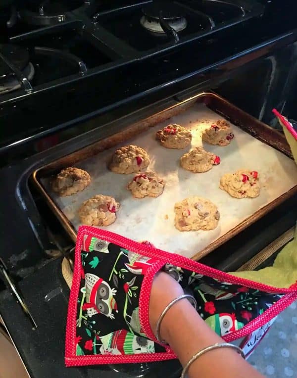 Image shows a woman holding a tray of cookies using a DIY pot holder.