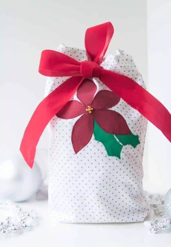Image shows a DIY applique gift bag with a ribbon.