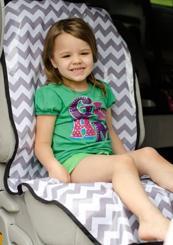 Little girl sitting inside a car with a car seat protector.