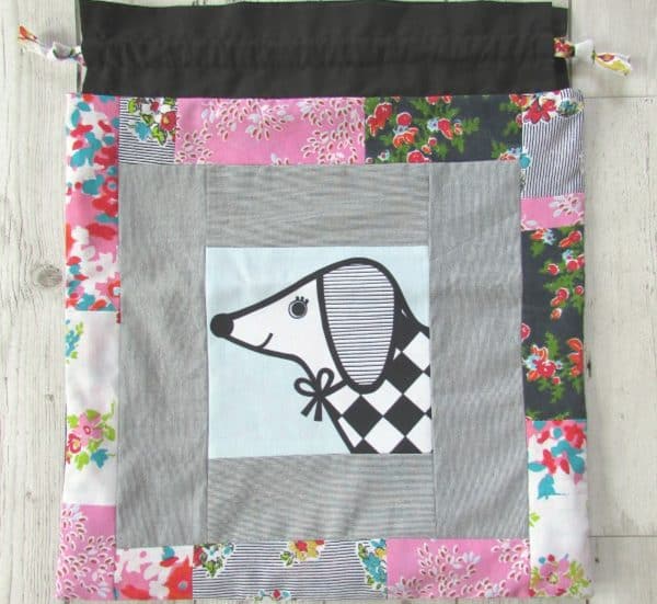 Image shows a drawstring patchwork toy bag with a puppy drawing on it.