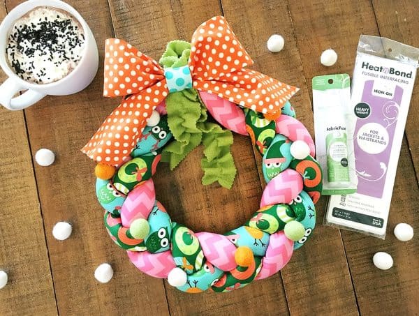 Image shows a christmas wreath with christmas decorations next to it.