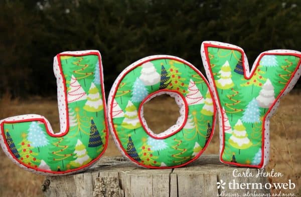 Image shows the word JOY in pillows with chrismas theme.