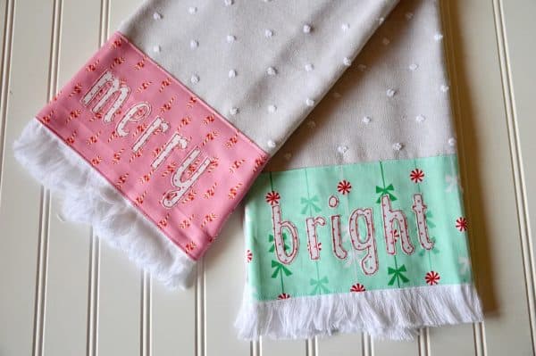 Image shows two kitchen towels with a christmas theme that say "merry" and "bright"