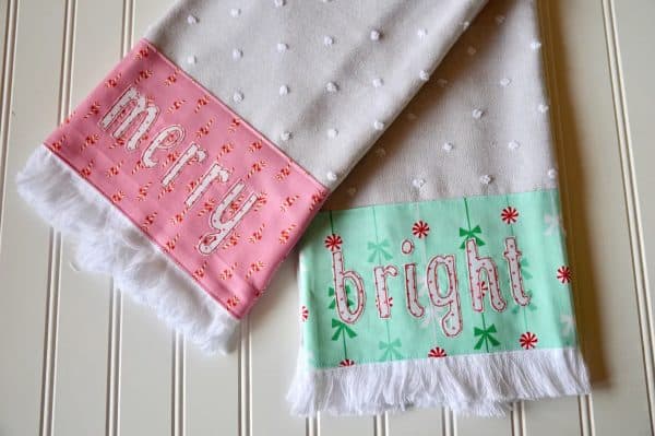 Image shows two kitchen towels with a christmas theme that say "merry" and "bright"