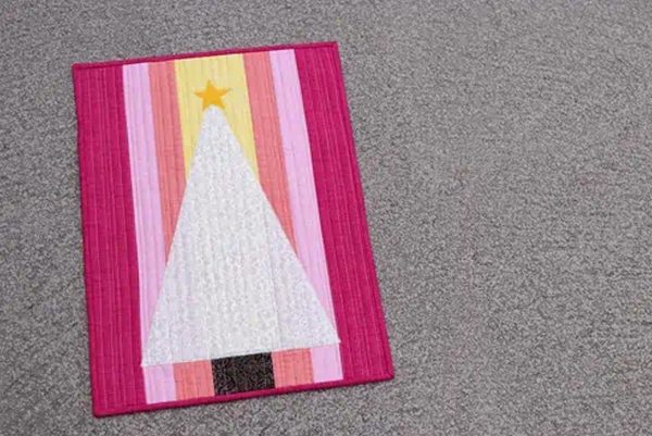 Image shows a candy christmas mini quilt on the floor.