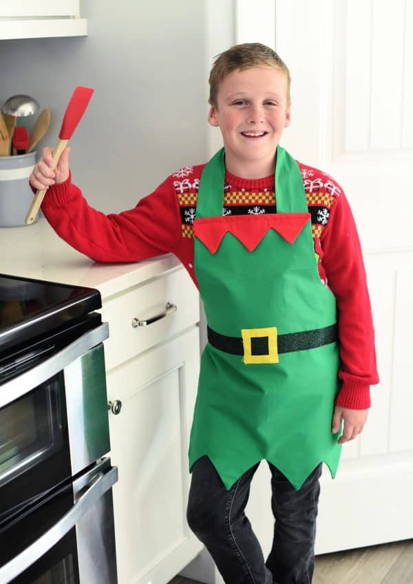 Image shows a young boy in a kitchen wearing an elf apron pattern.