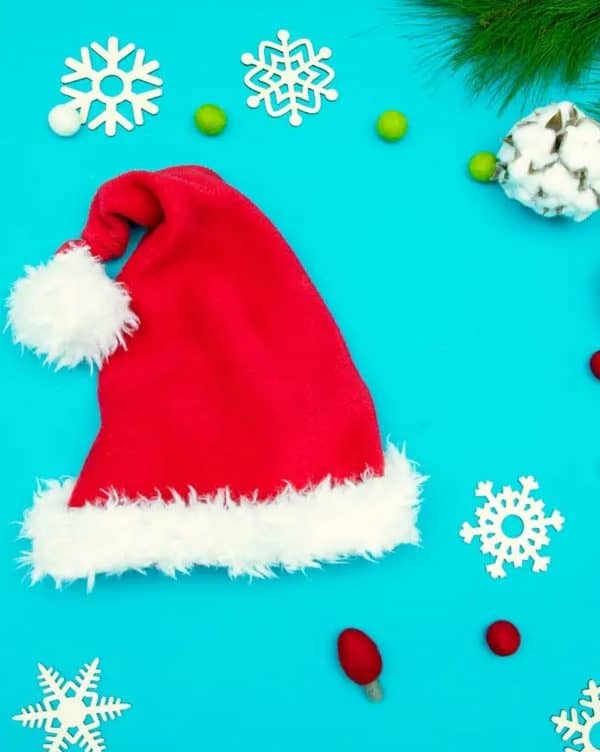 Image shows a santa hat in front of a blue background with christmas decorations.