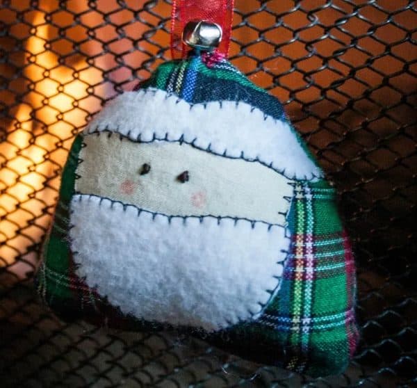Image shows a santa face ornament hanging from a ribbon.