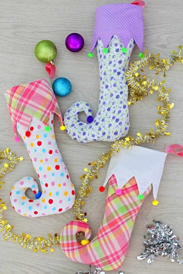 Image shows three elf stockings with colorful patterns and christmas decor.