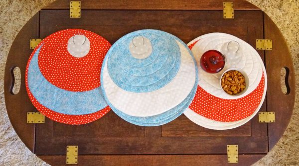 Image shows three festive placemats on. wooden table.