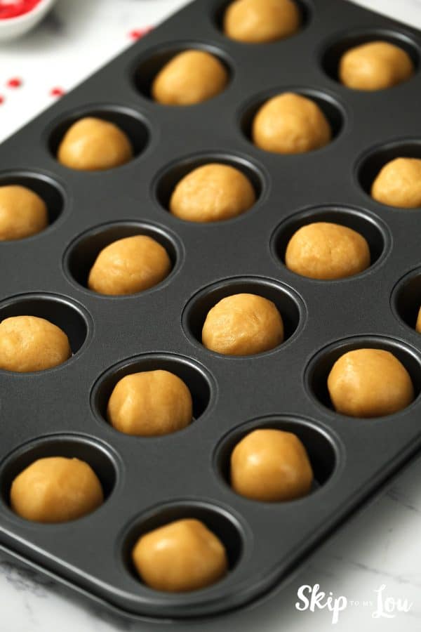 Black mini cupcake tin filled with cookie balls, ready to bake, by Skip to my Lou.