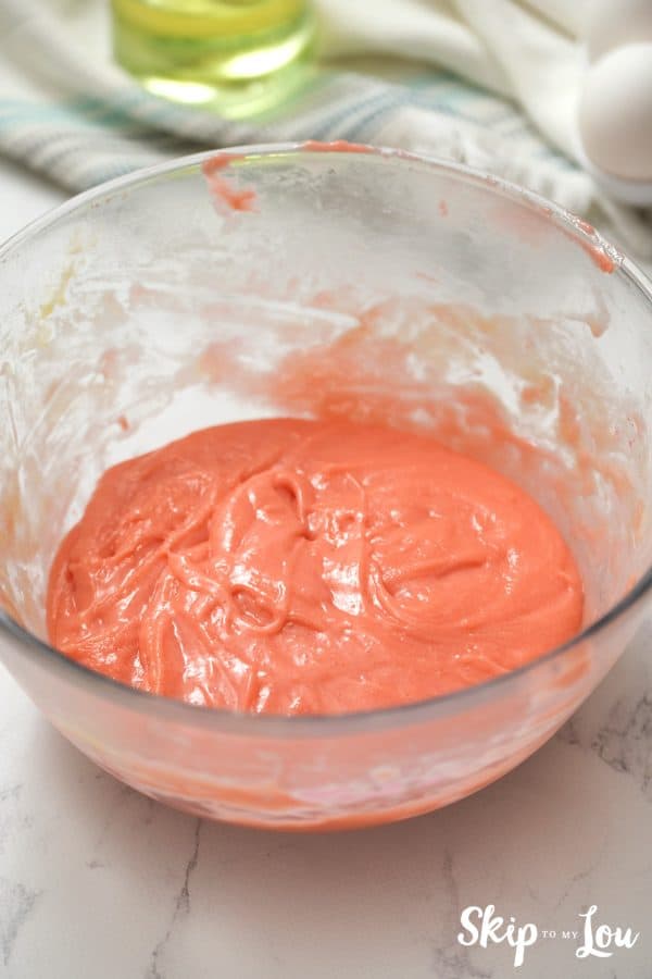 Glass mixing bowl with pink strawberry cake mix batter inside, by Skip to my Lou.