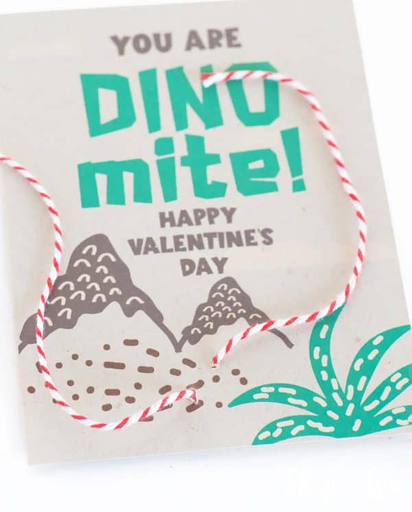 Brown card with a dinosaur Valentine saying, red and white string laced through the back of the card by Skip to my Lou.