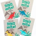 four dinosaur valentine cards with different colored plastic toy dinosaurs attached