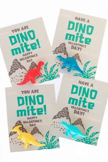 four dinosaur valentine cards with different colored plastic toy dinosaurs attached